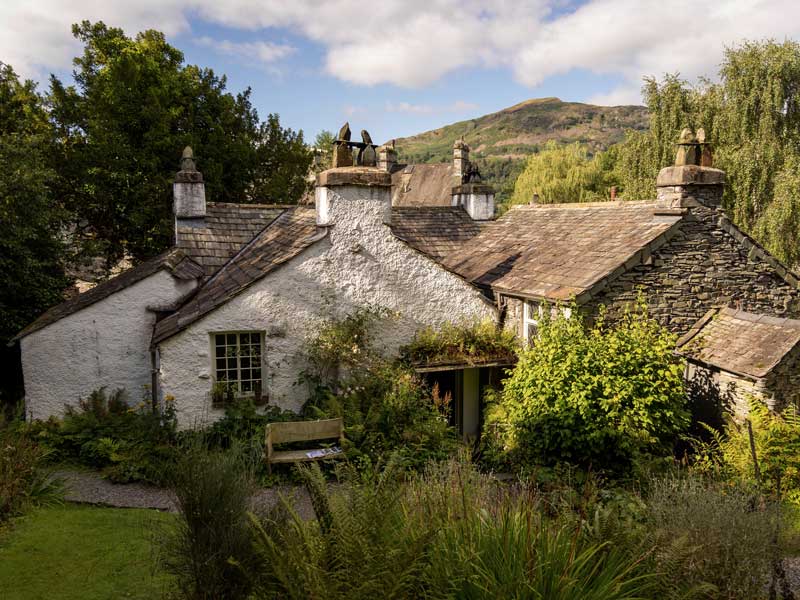 Photo looking at Dove Cottage surrounded by lush foliage on a sunny day.