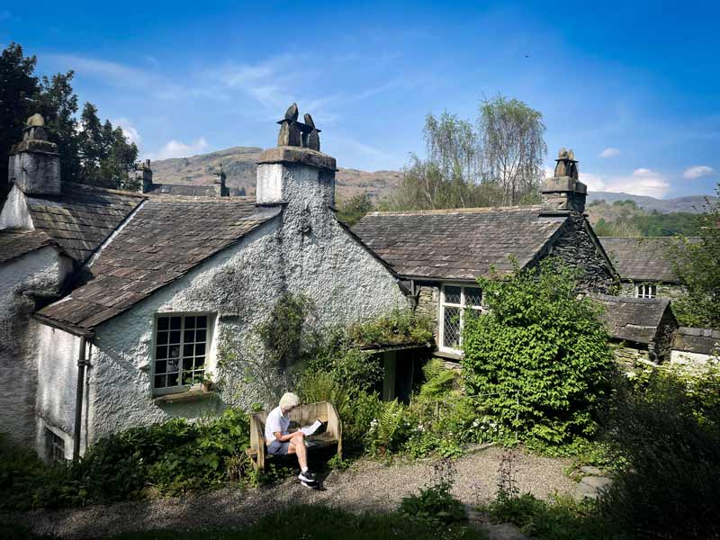 Photo looking at Dove Cottage surrounded by lush foliage on a sunny day.