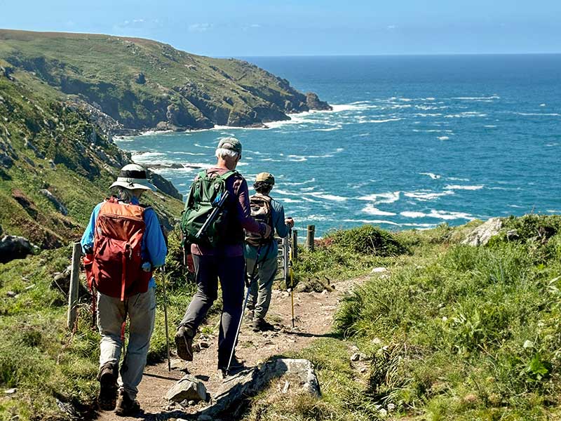 Three hikers following a coastal path